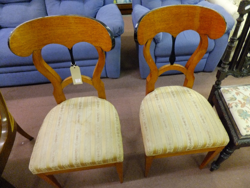 A pair of early 19th century Empire chairs having ebonised central splat upholstered seat resting on