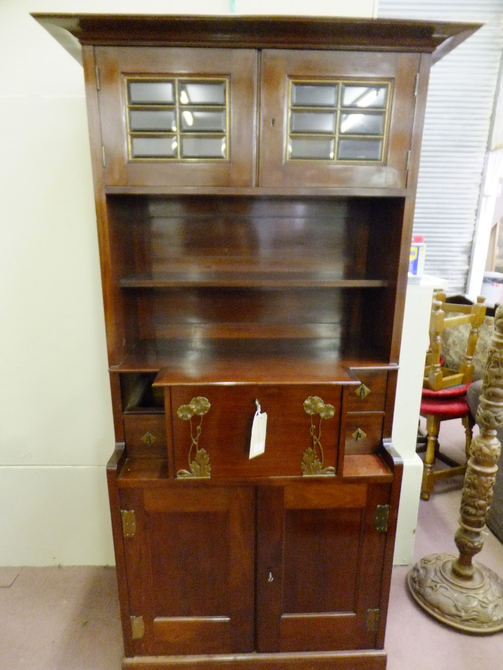 An art nouveau mahogany veneered bureau having two glazed doors above a shelf the full front flanked