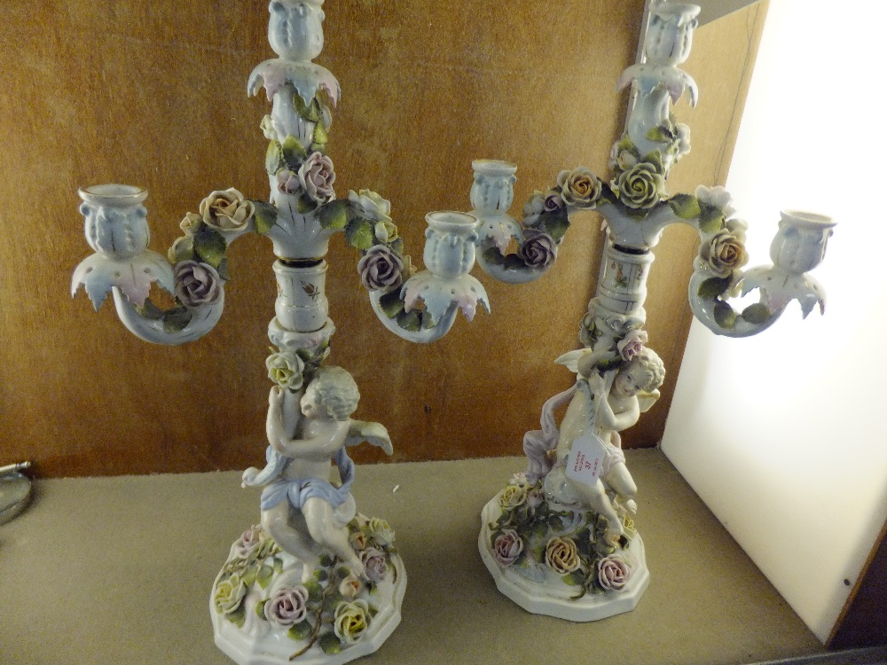 A pair of German porcelain candelabra's, the stems with winged cherubs amongst a bed of roses, the