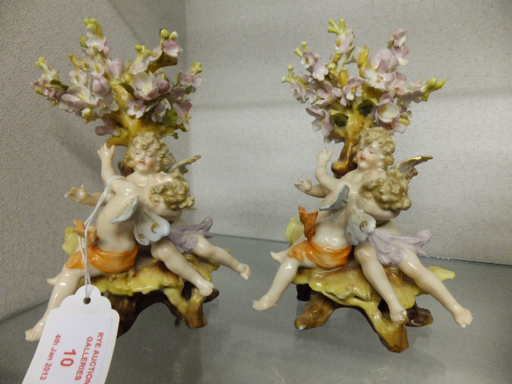 A pair of German porcelain figures depicting playing imps under flowering tree, 6" high A/F