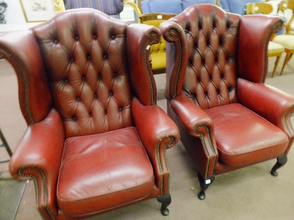 A pair of burgundy studded leather button-back armchairs resting on cabriole legs