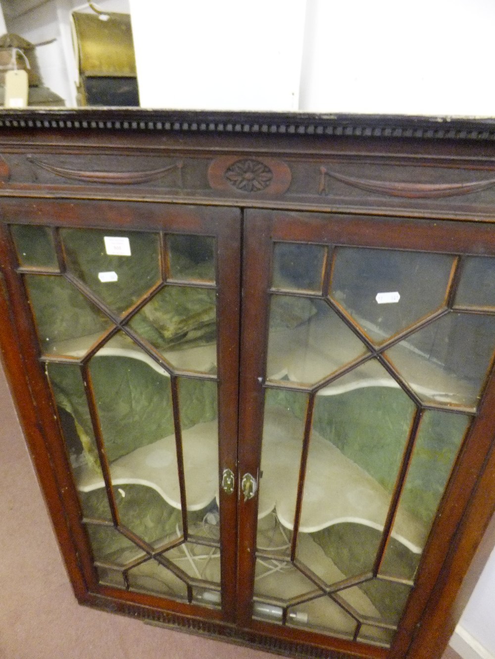 A George III mahogany hanging corner cupboard having carved cornice and astragal glazed doors