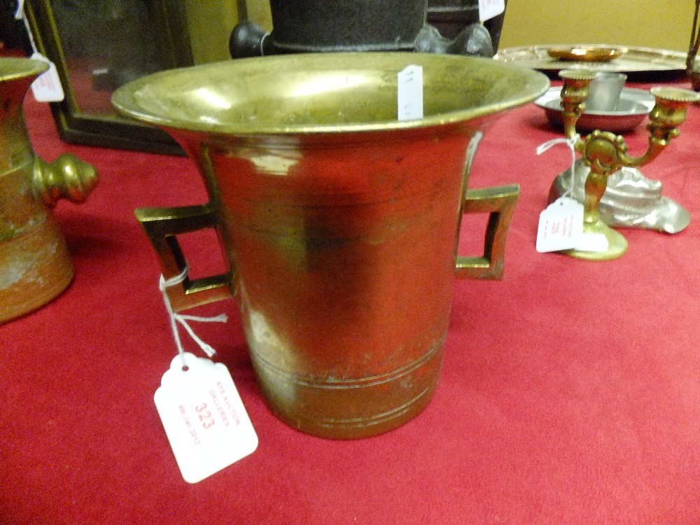 A late 19th century early 20th century bell shaped brass mortar with two handles, no pestle