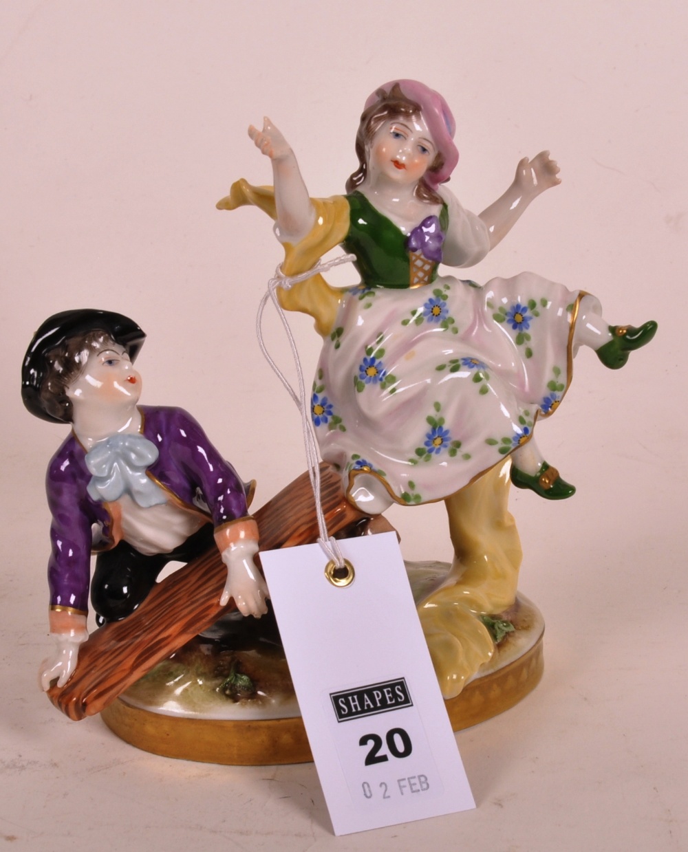 Continental porcelain figure group depicting a gallant and his companion on a see-saw, raised on