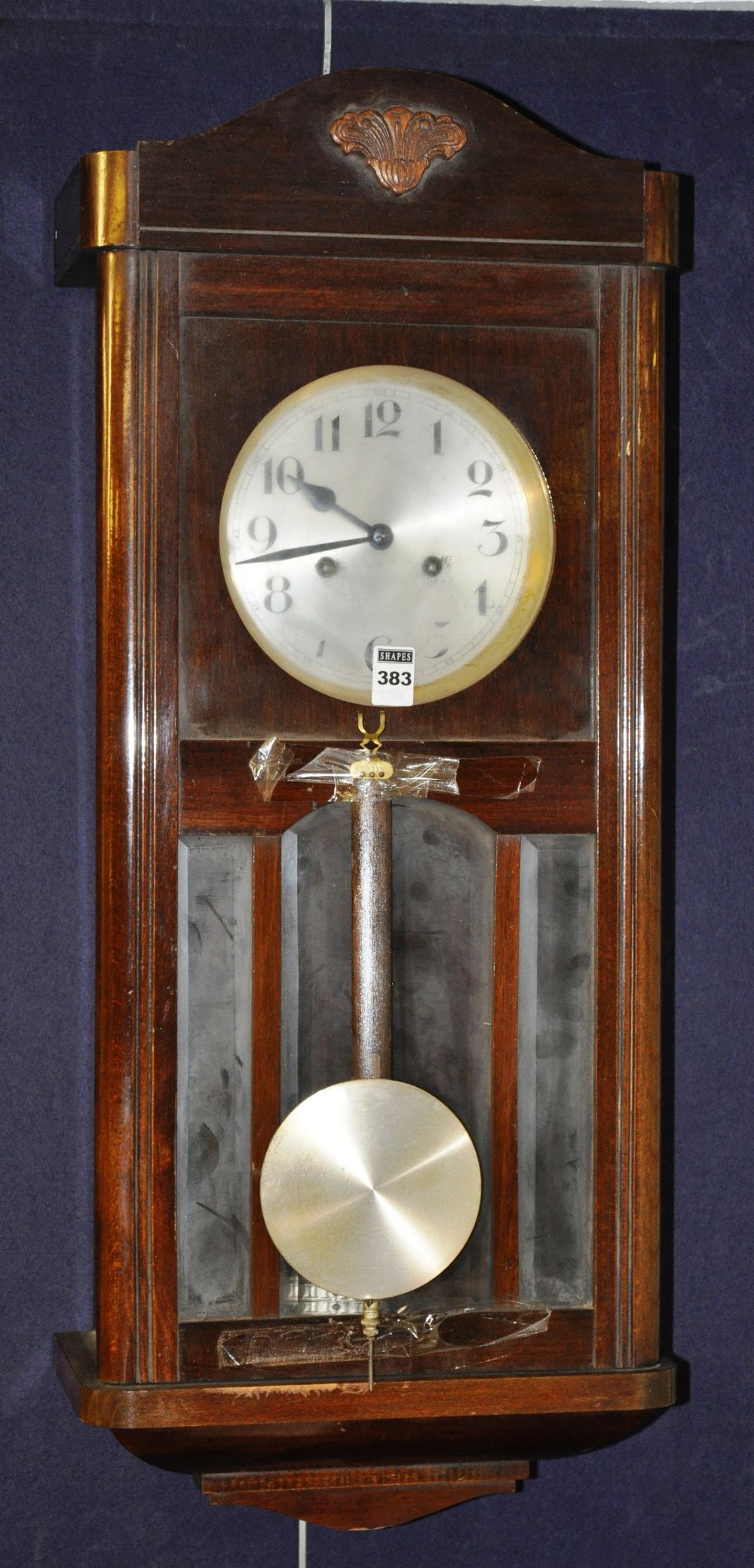 A mahogany cased wall clock, the arched pediment over circular brush metal face with Arabic