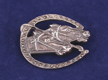 Silver horse-shoe brooch encrusted with semi-precious stones