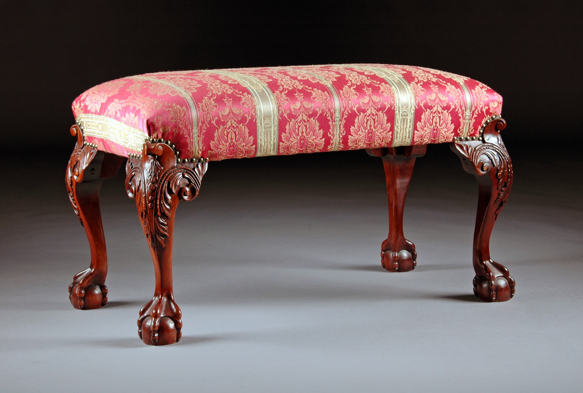 A CHIPPENDALE STYLE UPHOLSTERED MAHOGANY BENCH, 20TH CENTURY, upholstered with pink and gold