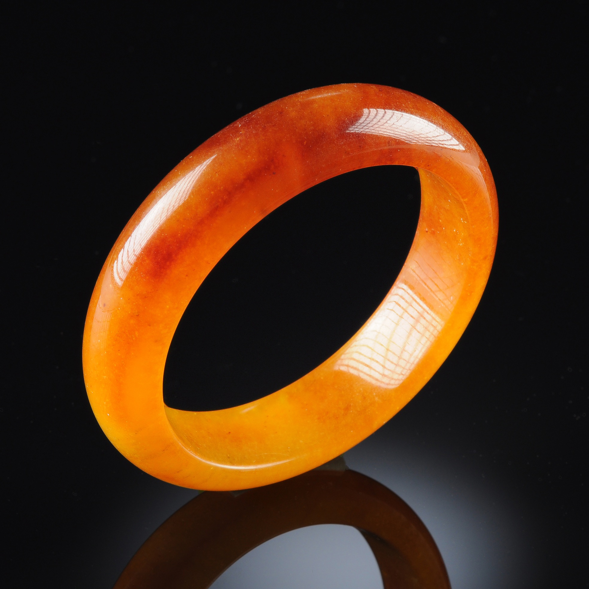A CHINESE CARVED AMBER JADEITE BANGLE BRACELET, of circular form with pale mustard tones shading