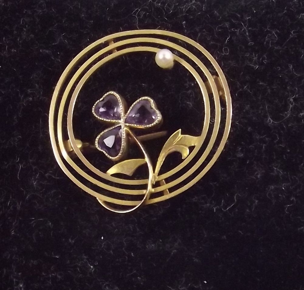 A 9ct gold circular brooch with amethyst set trefoil and seed pearl