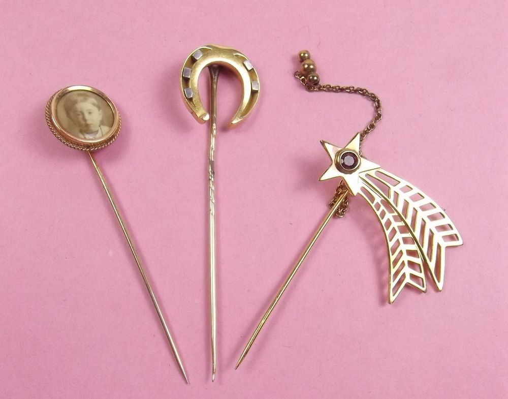 A 9 carat gold shooting star form stick pin set red stones and two yellow metal stick pins