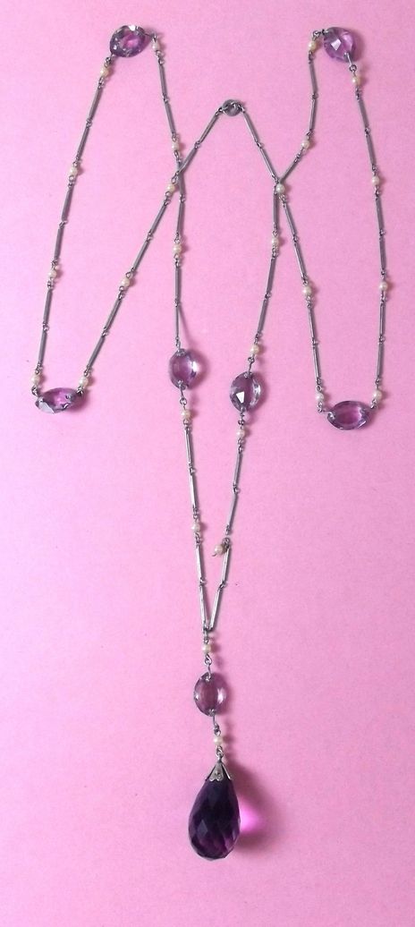 An early 20th century French long white metal necklace suspended `amethyst` beads and seed pearls,