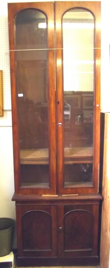 A 19th century mahogany tall bookcase with glazed doors over panelled doors, missing cornice and