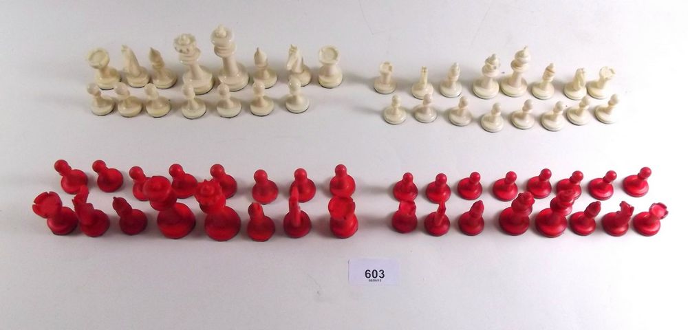 A red and ivory chess set (one pawn missing) and another smaller set complete, boxed