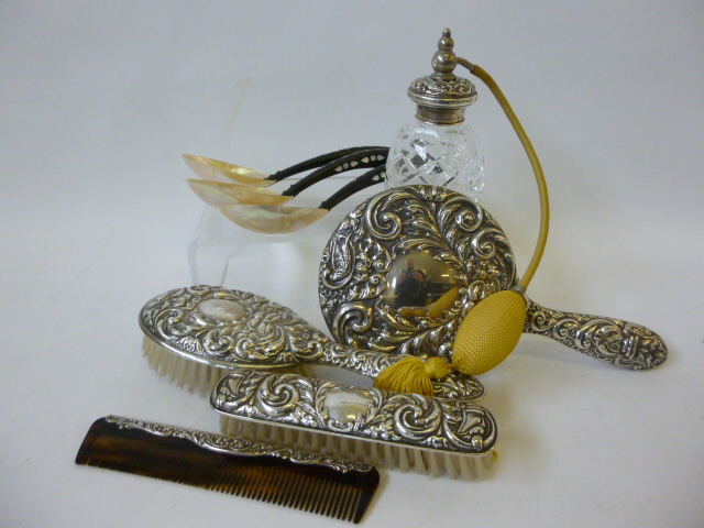 A five piece heavily embossed silver backed dressing table set, comprising hair brushes, comb,