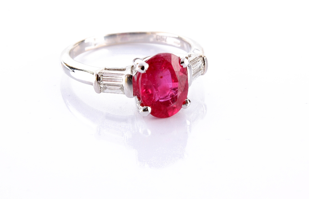 A fine modern ruby and diamond ring, the oval cut ruby approx. 2.35ct with a pair of baguette cut