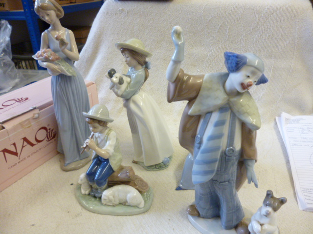 A group of Nao figures including a clown with a dog, shepherd boy playing pipe, and three others,