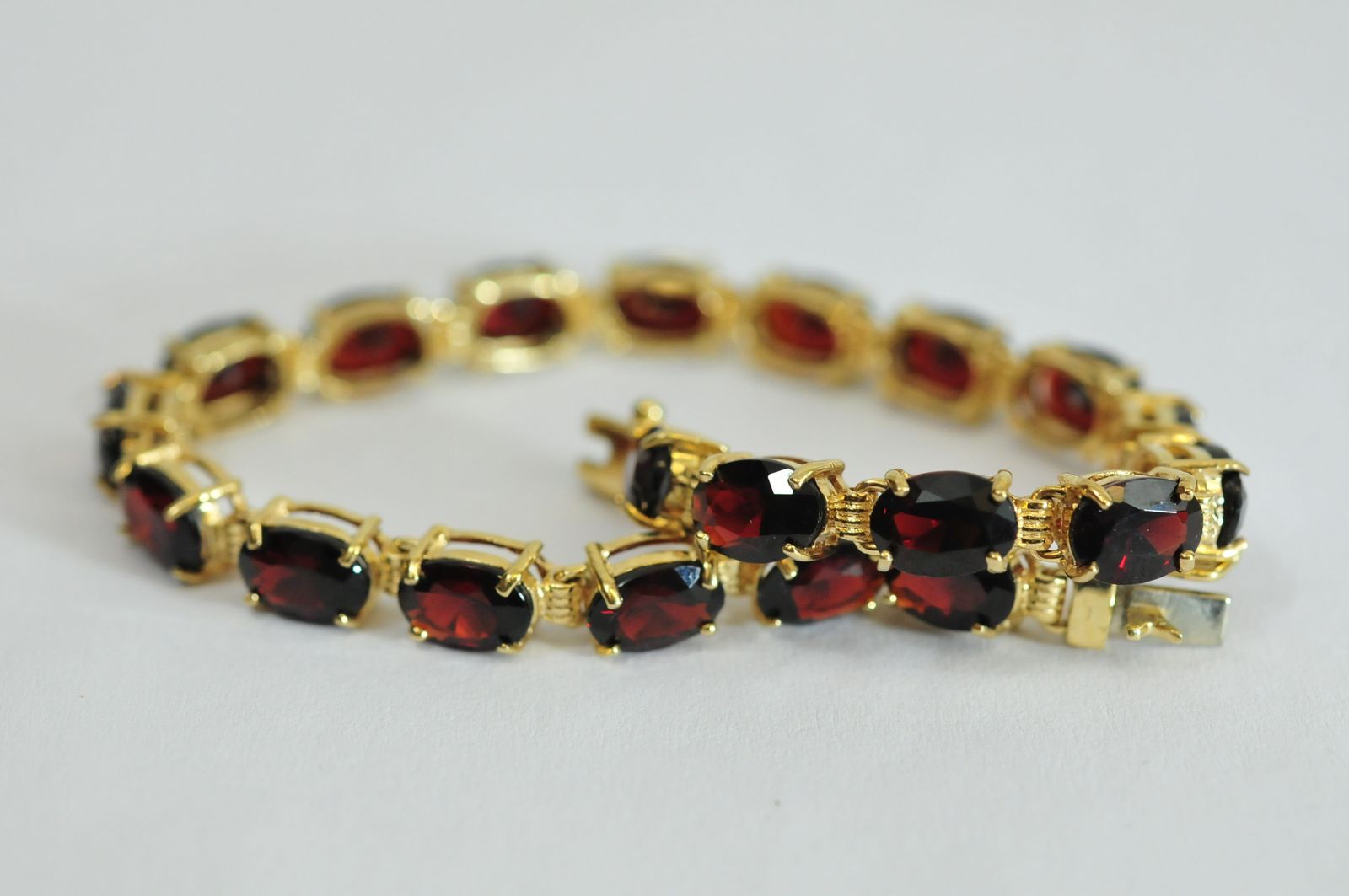 A ladies 9ct gold line bracelet set with a single row of oval cut garnets