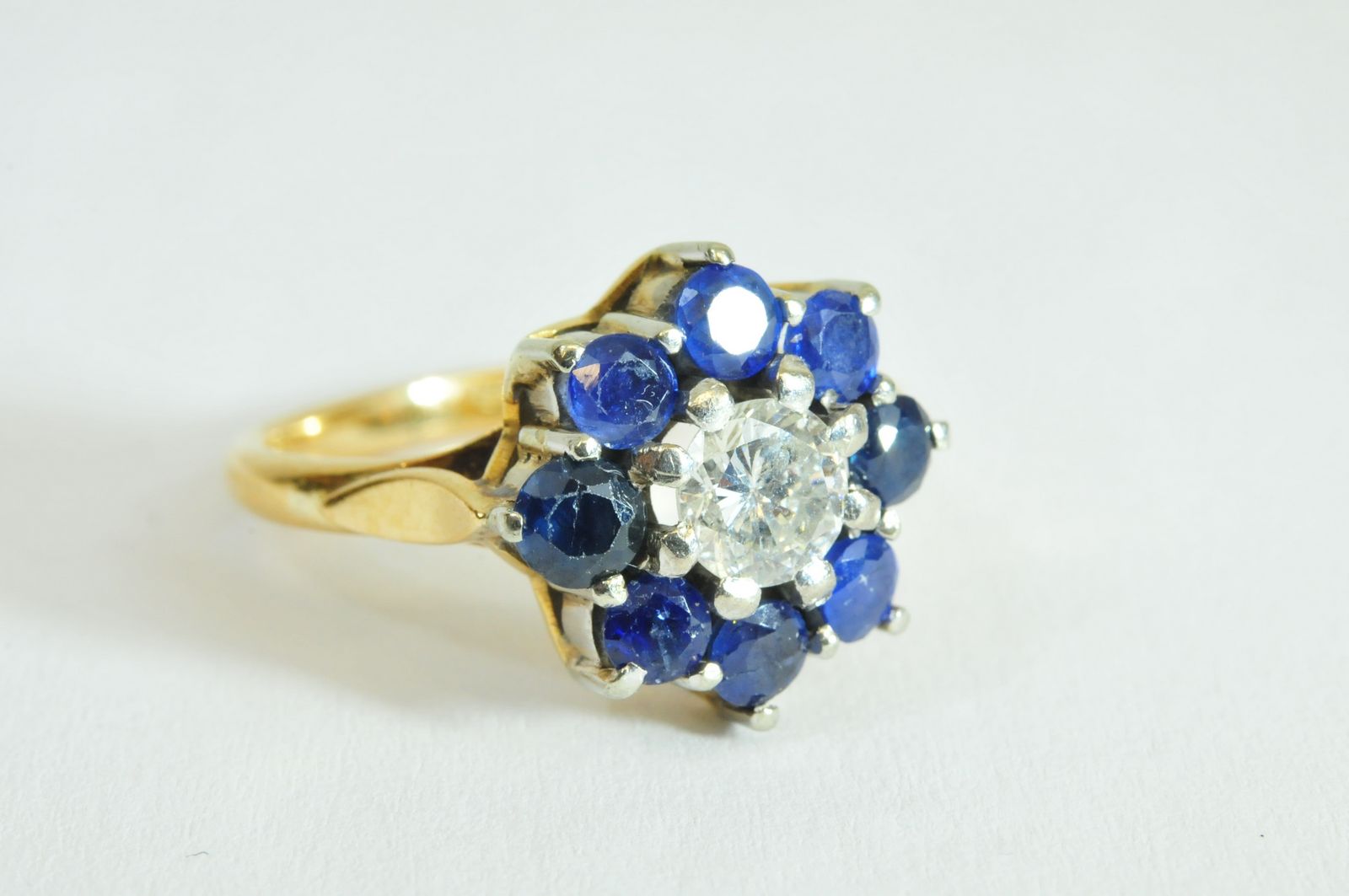 A ladies 18ct gold ring set with a central brilliant cut diamond with round cut sapphire surround