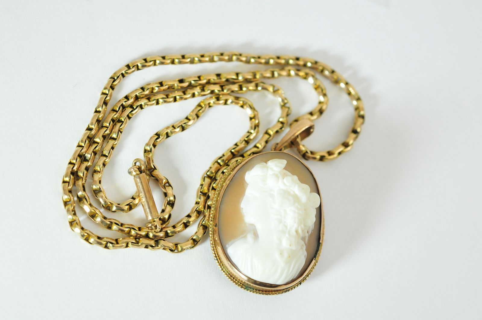 A 9ct gold mourning pendant inset with raised cameo having glass back panel, on a conforming gold