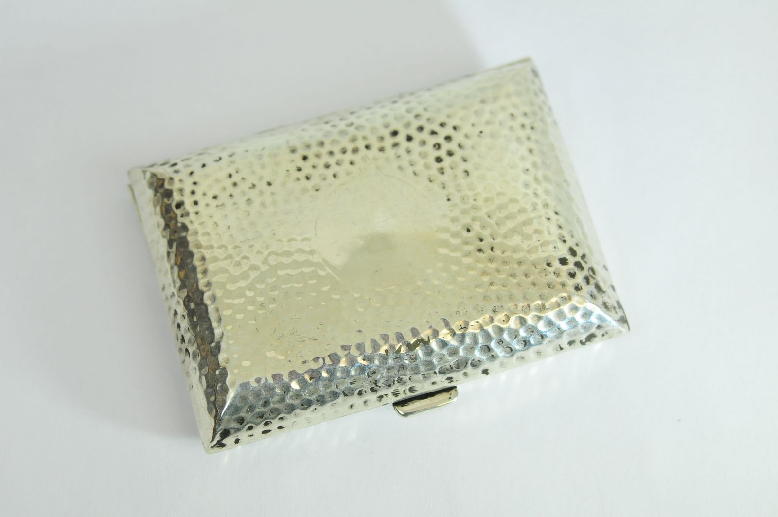 A silver cigarette case with Birmingham hallmarks for 1907, having beaten design with silver gilt