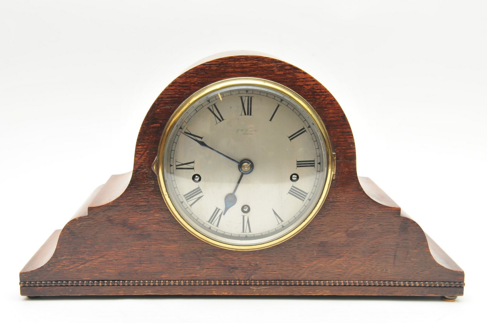 An oak cased Napoleon hat shaped mantle clock, the silvered dial with Roman numerals and inscription