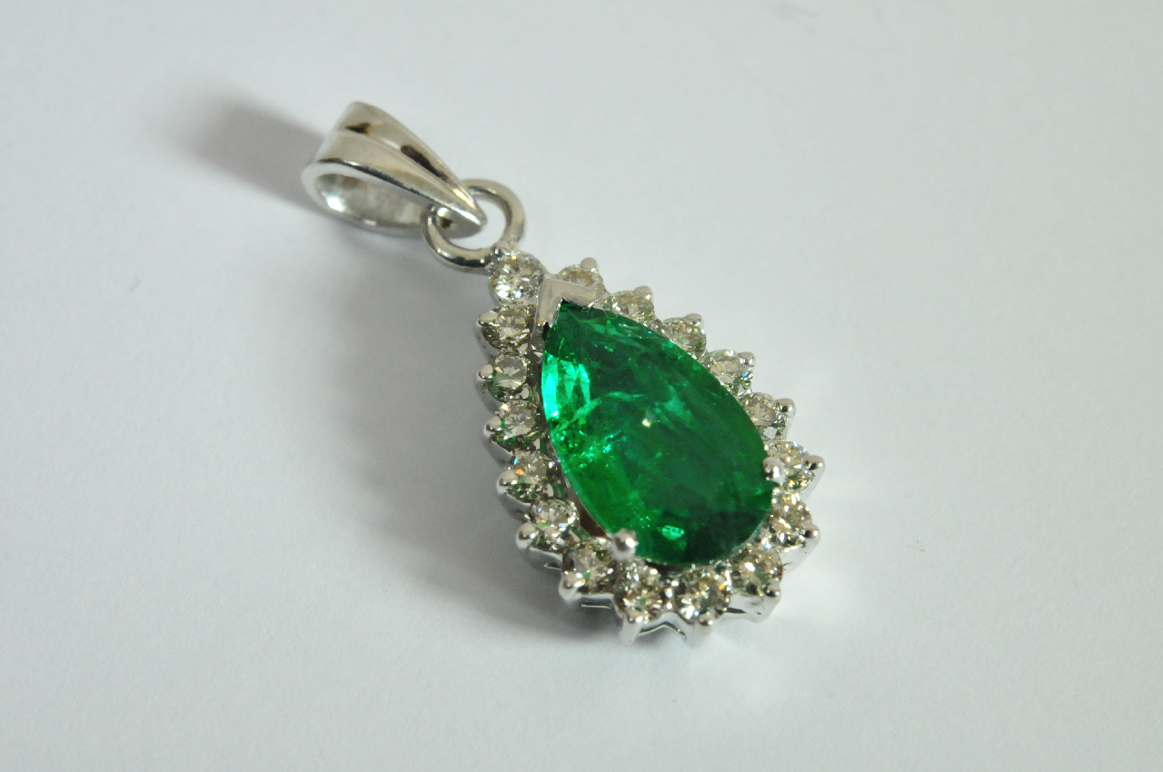 An 18ct white gold pendant set with a central pear cut emerald of 2.00ct surrounded by 0.62ct of