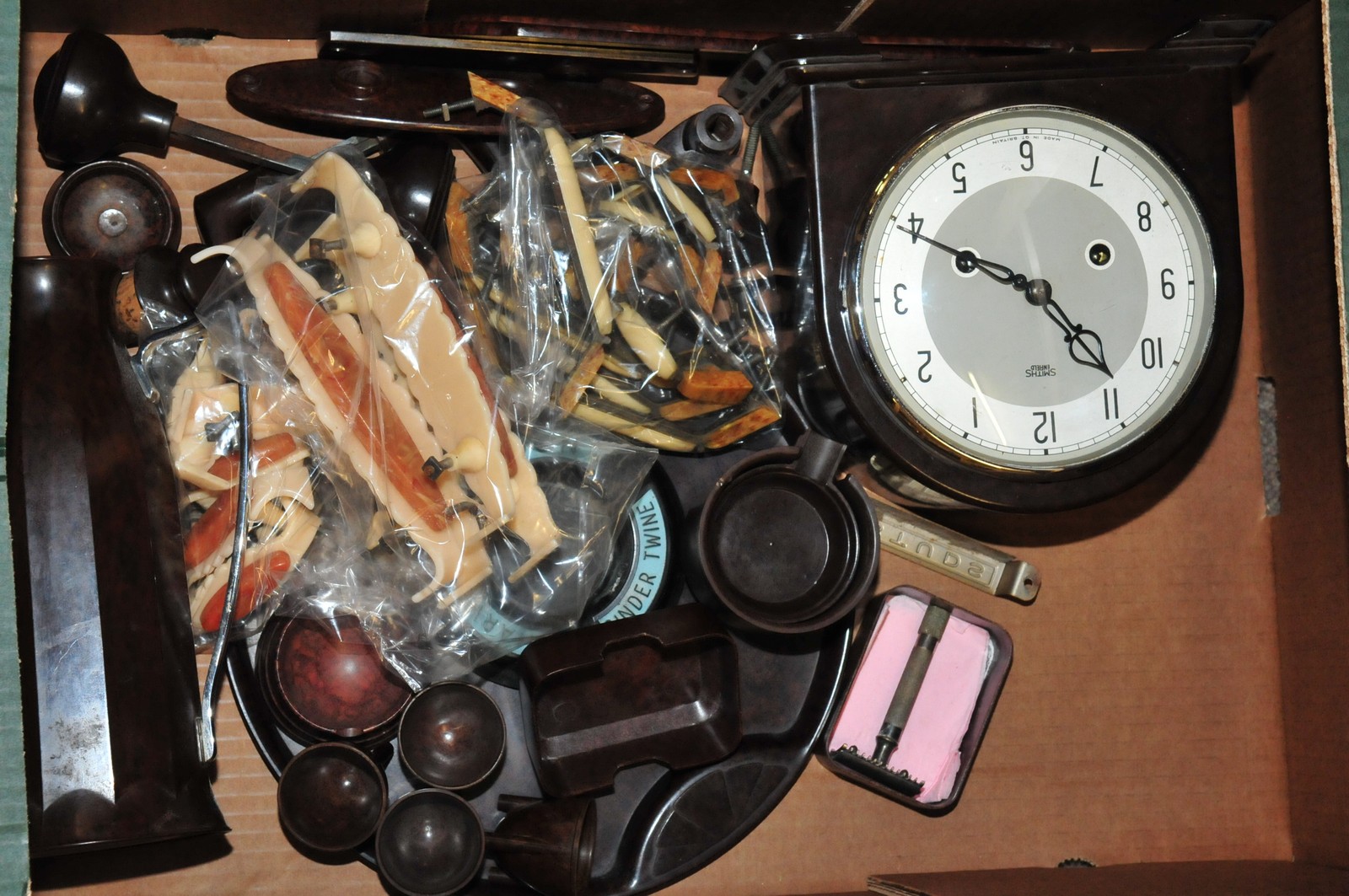 A box of mixed Bakelite items including a clock and door handles