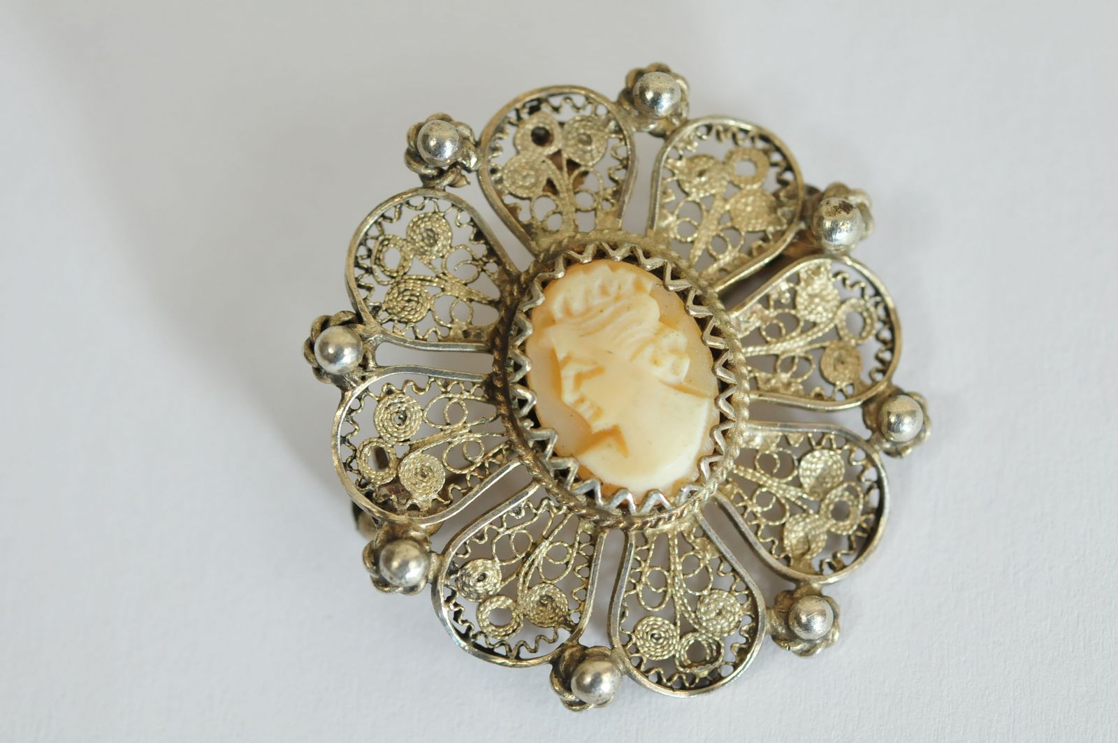 A white metal filigree brooch with small cameo of a lady.