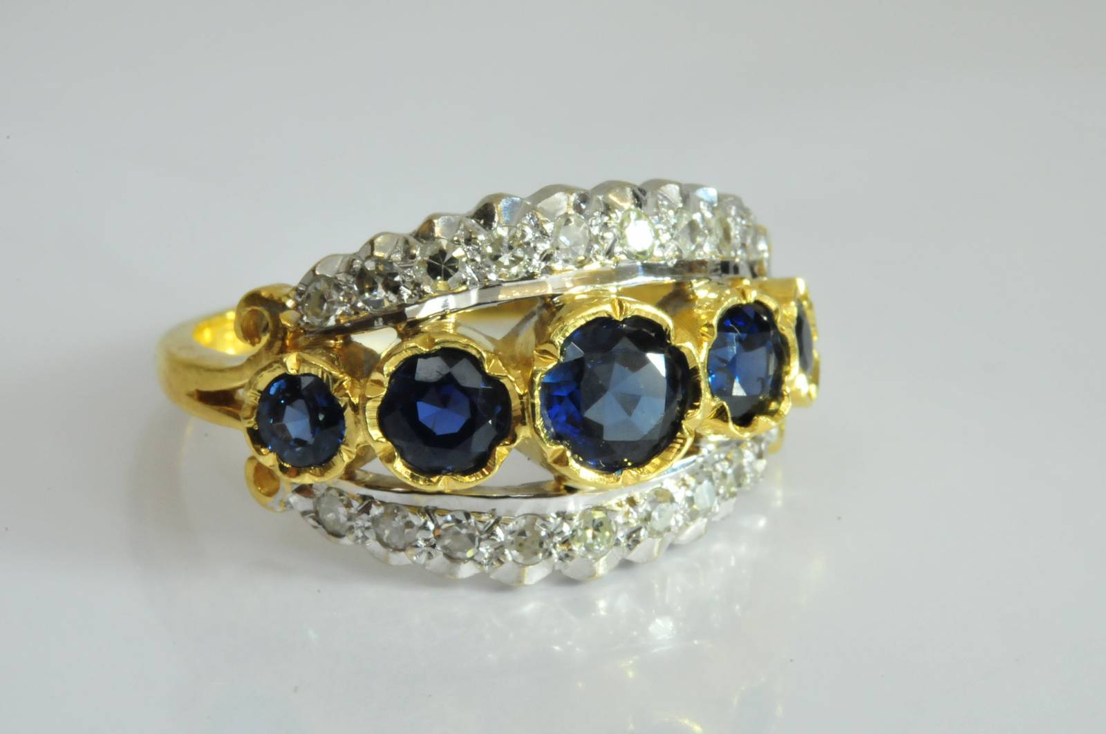 A ladies 18ct yellow gold ring set with a central row of five graduating blue sapphires flanked by a