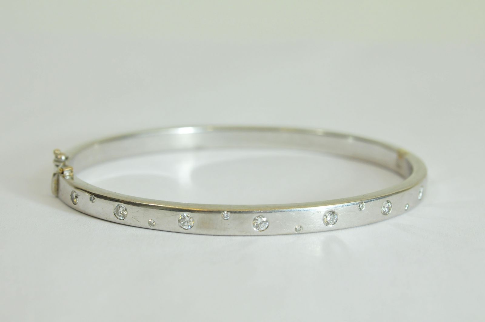 A ladies 9ct white gold bangle flush set with alternating staggered brilliant cut diamonds of