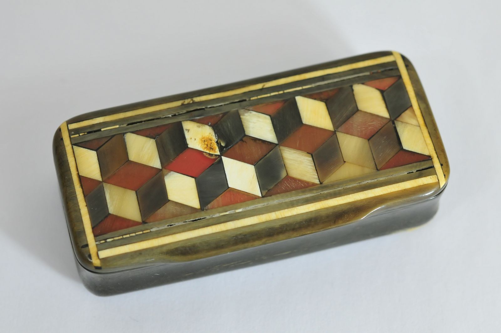 A horn snuff box, the hinged lid having inlaid decoration in a block pattern.