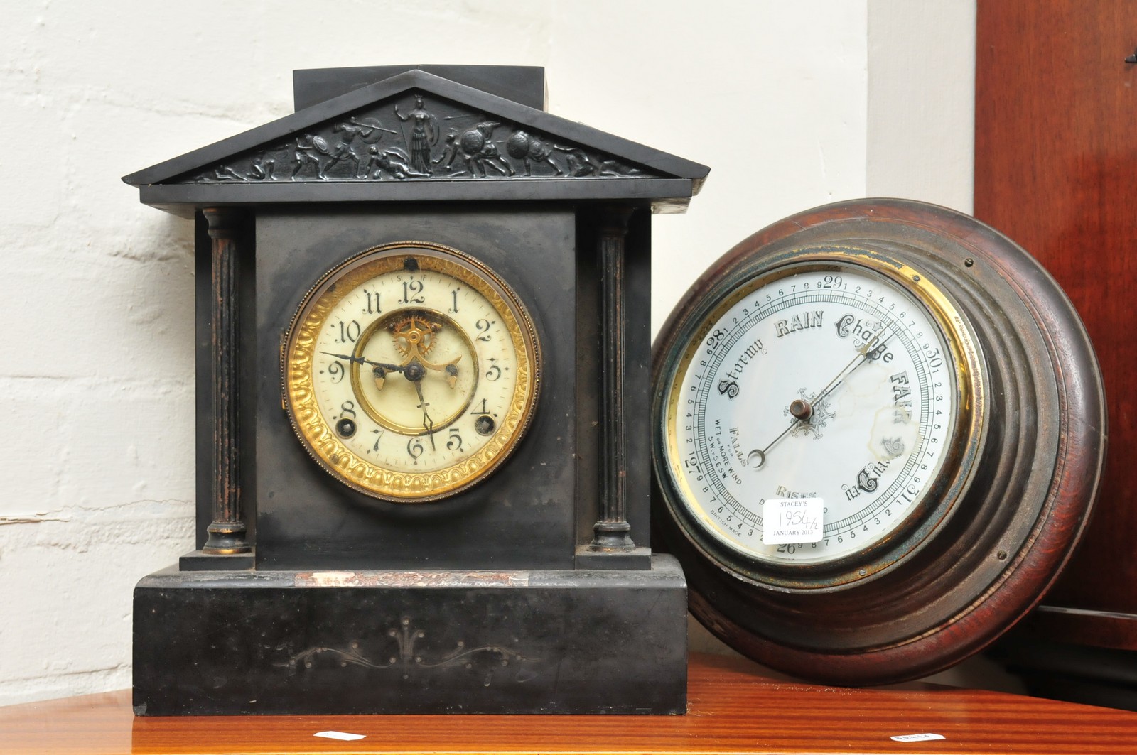 A Victorian black slate mantel clock and an aneroid barometer