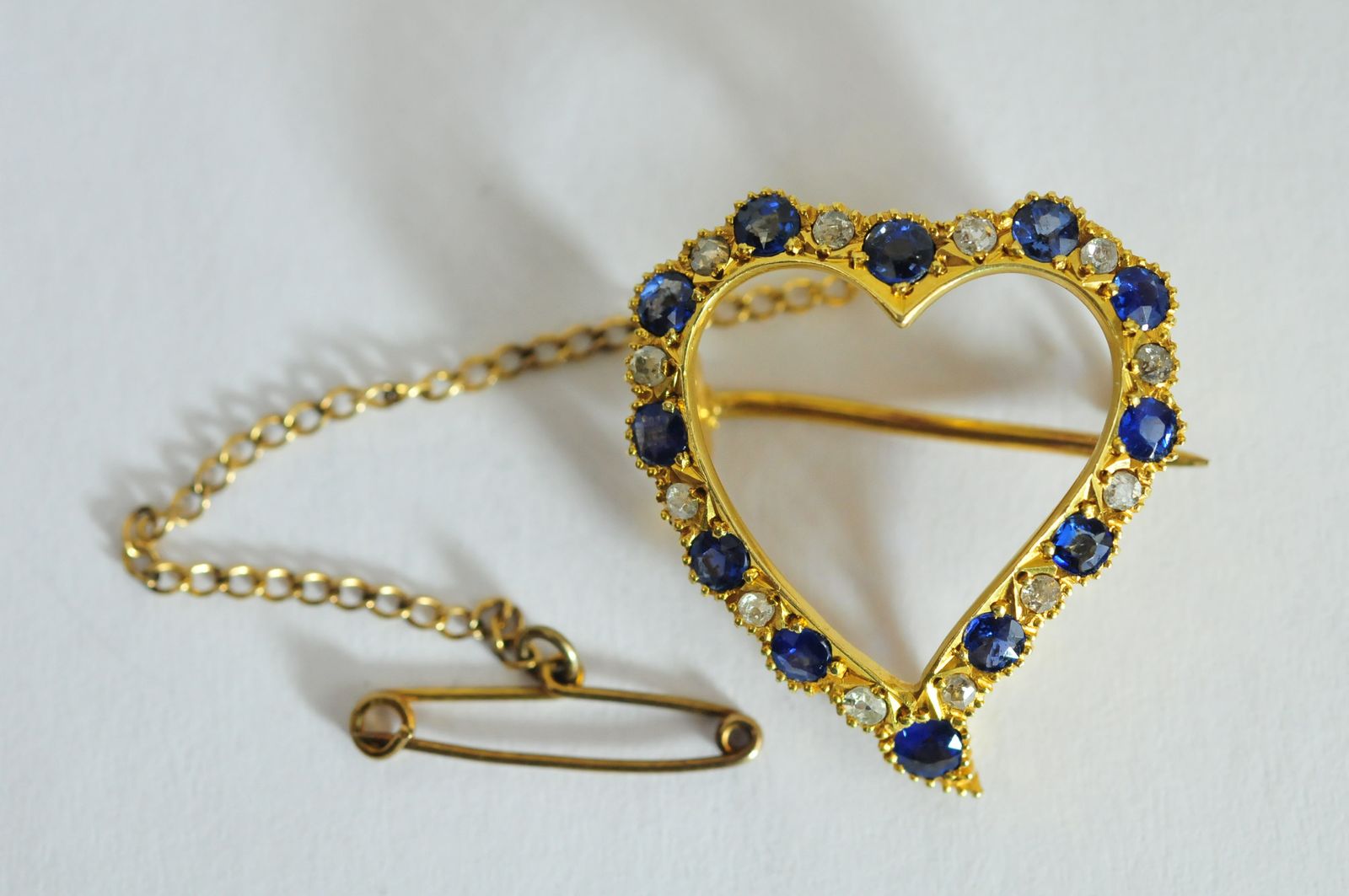 A ladies 15ct yellow gold heart shaped brooch set with alternating sapphires and diamonds