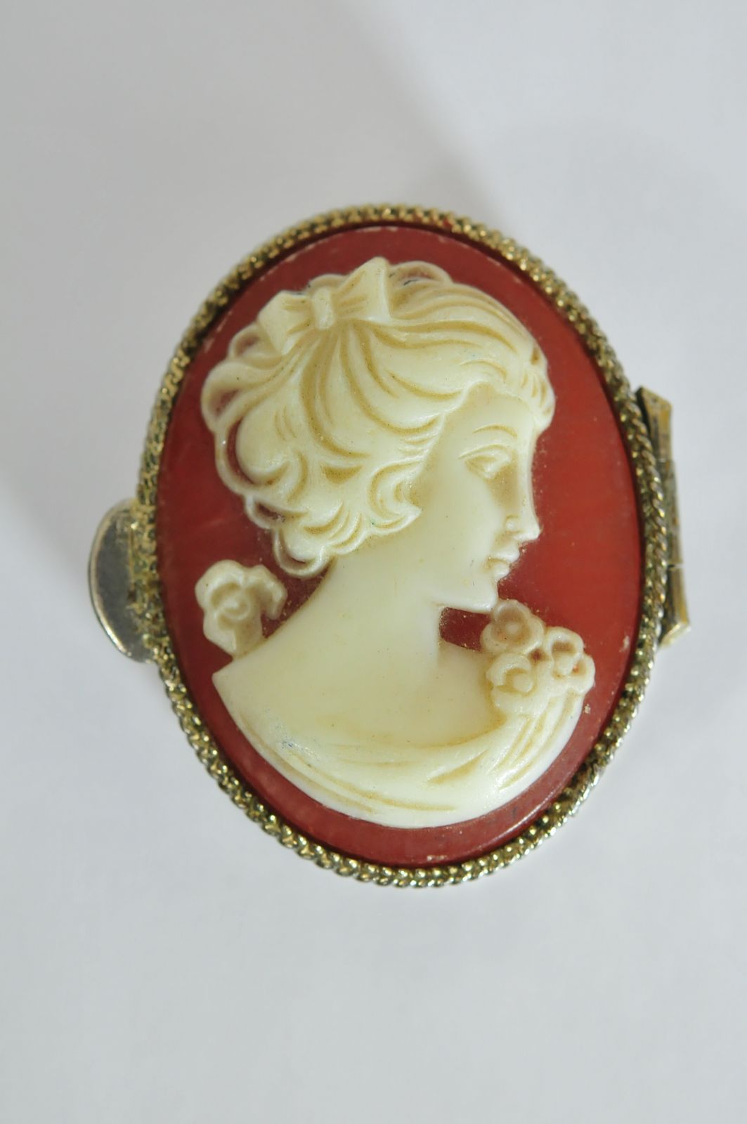 A white metal pill box with hinged lid having cameo decoration to the lid and engraved decoration.
