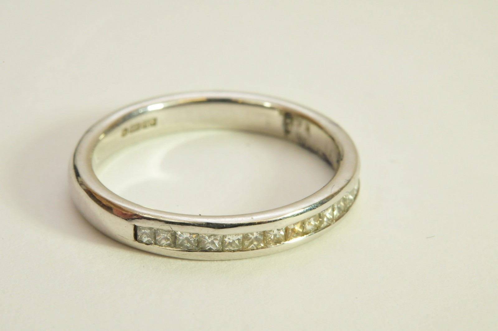 A ladies 18ct white gold half eternity ring, channel set with a single row of princess cut diamonds