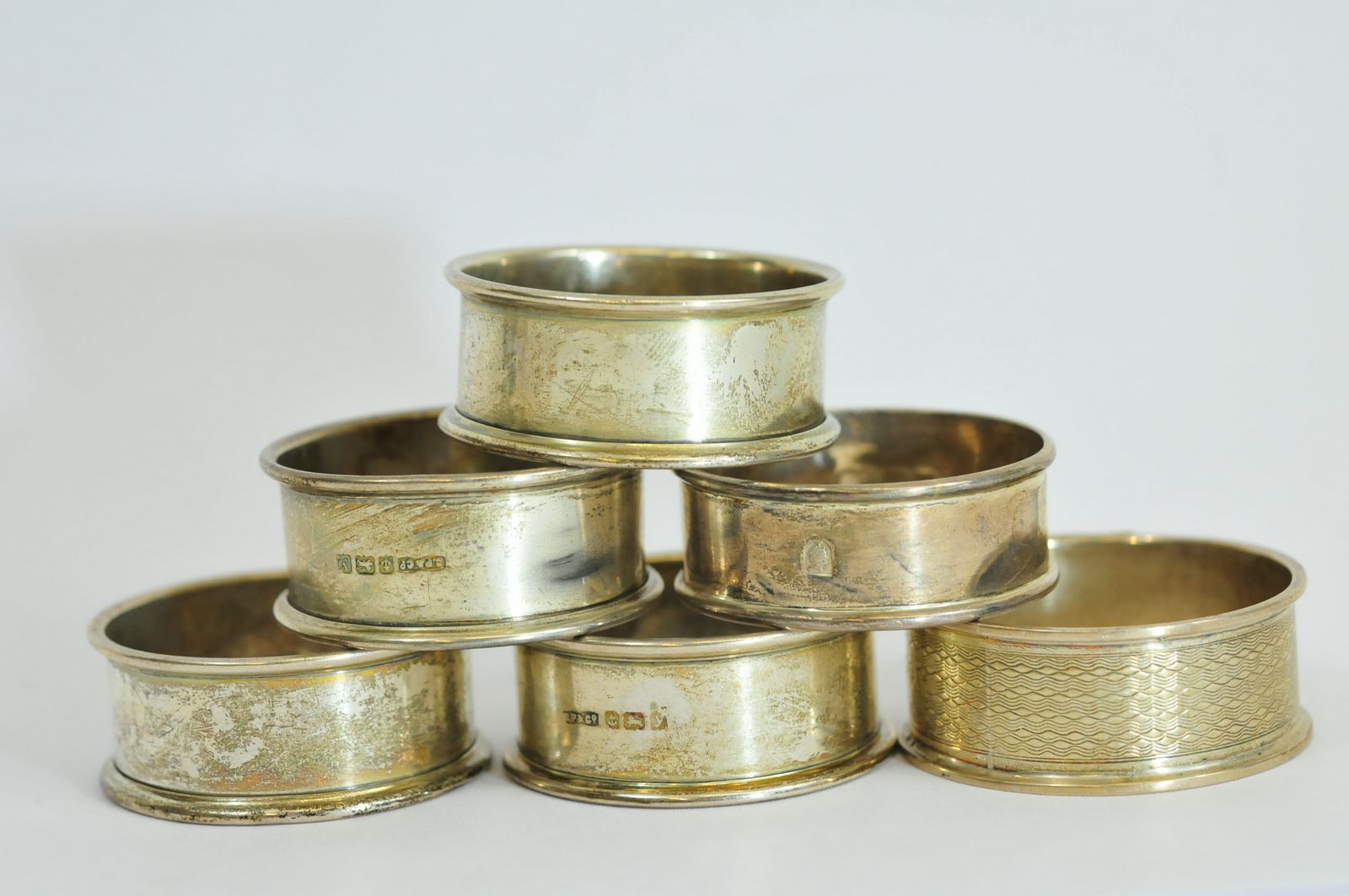 A collection of six silver napkin rings of varying design
