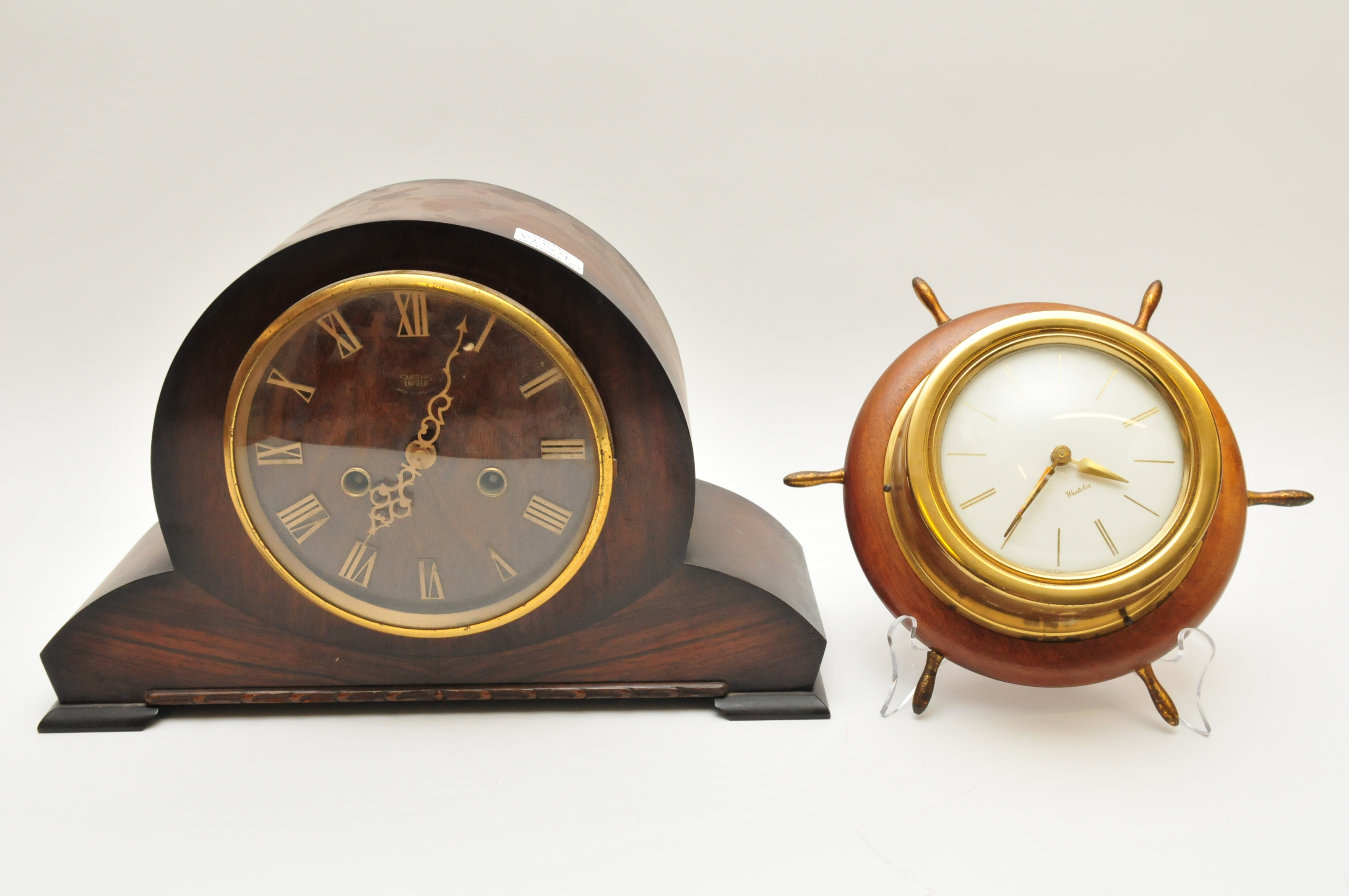 A brass wall clock with simulated ships wheel surround, together with a Smith's Enfield mantle