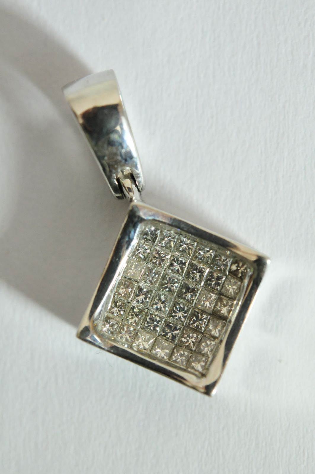 A ladies 18ct white gold pendant of square form pave set with princess cut diamonds in a concave