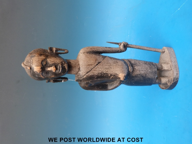 An African carving of a warrior standing with a spear and elongated ear lobes.