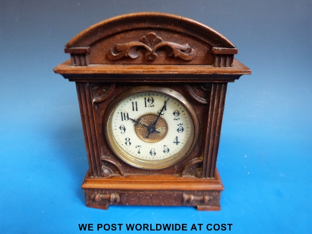 An American mantel clock in carved oak case, ivory chapter ring with Arabic numerals, keyless