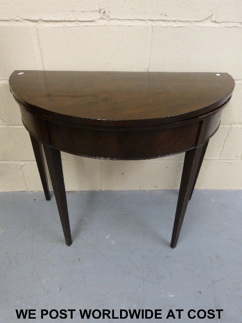 A Georgian demi lune mahogany fold over card table with inset felt top, raised on four square