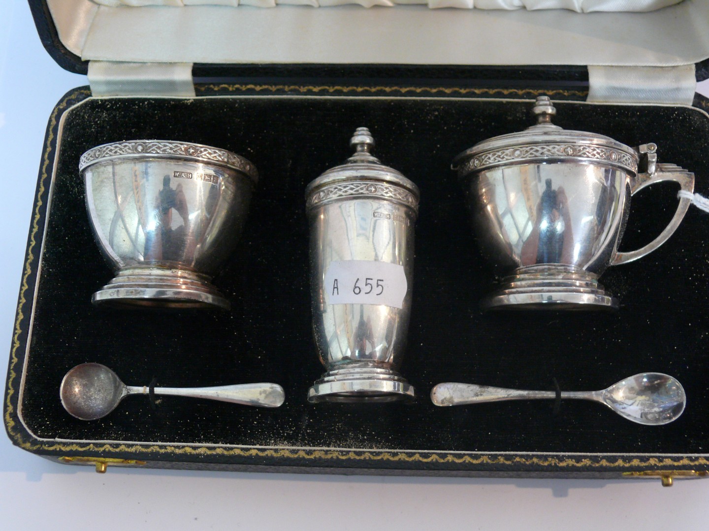 A silver three piece condiment set, having circular stepped bases, plain body with Celtic style