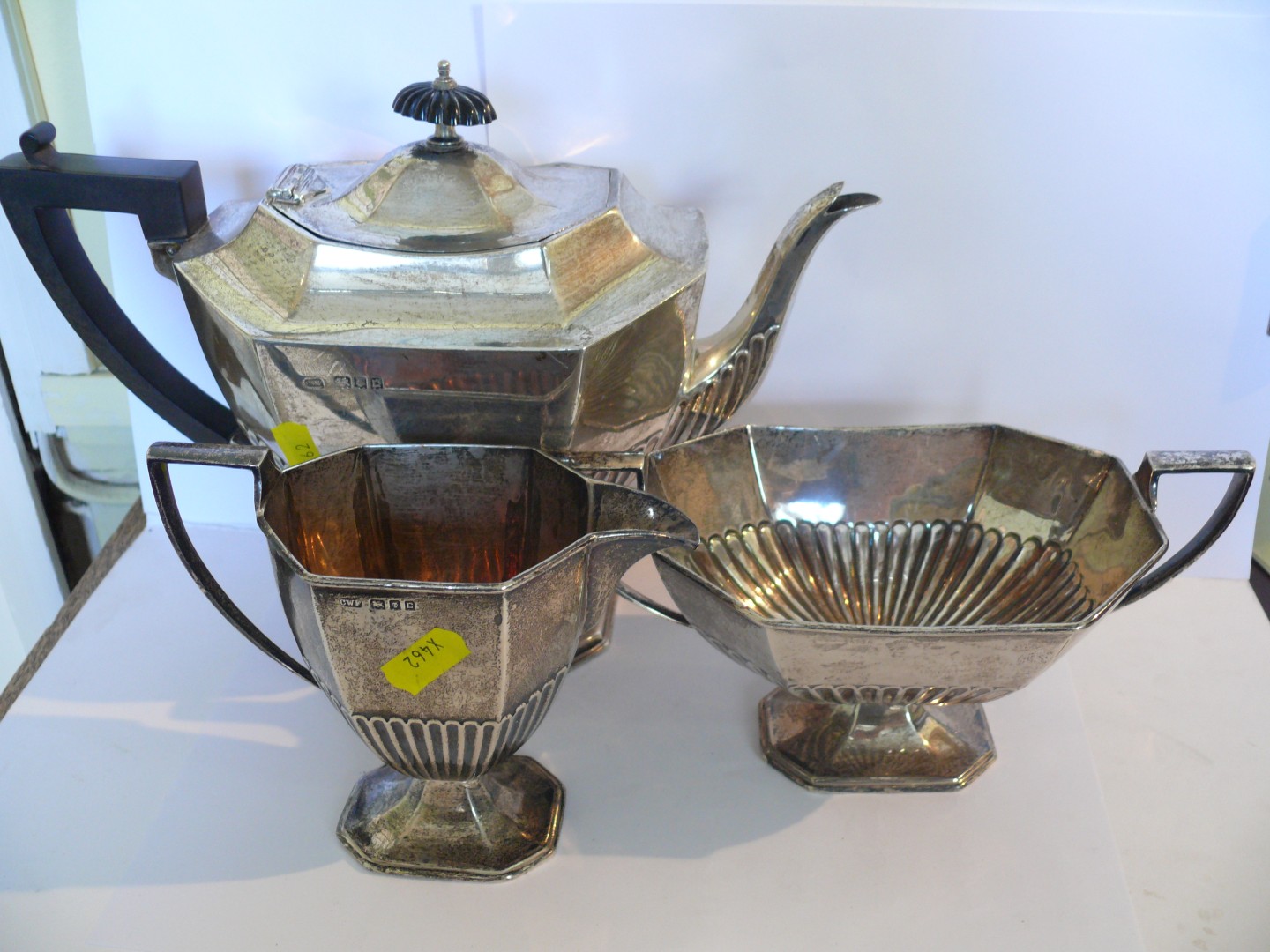 An Edwardian silver three piece teaset of octagonal form, having plain upper body with reeded bottom