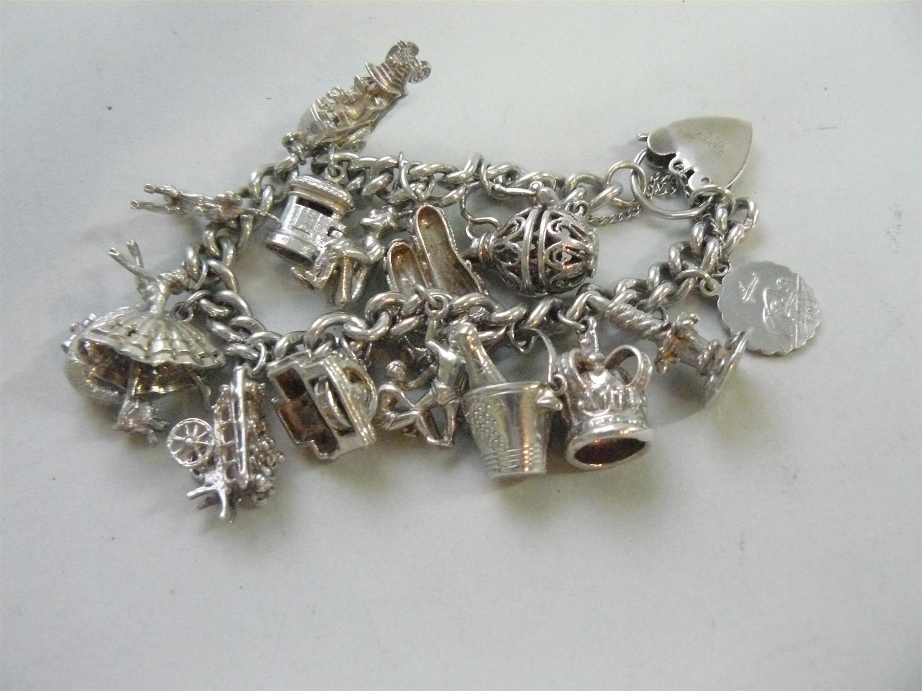 A silver charm bracelet with padlock clasp, with sixteen charms attached, the bracelet and one charm