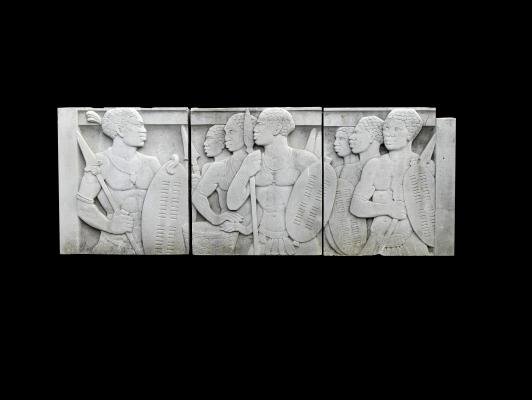 A carved Portland stone plaque the three panels carved in relief with Zulu warriors 114cm.; 45ins