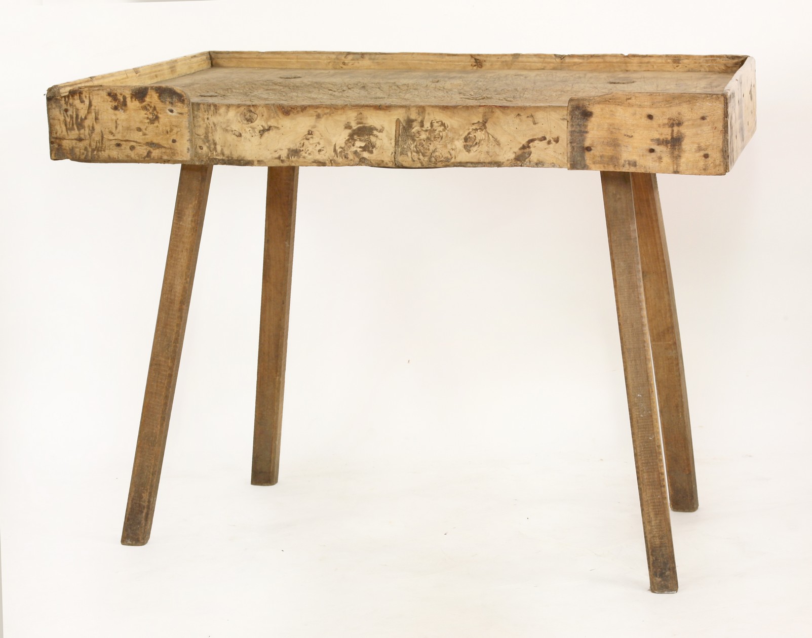 A country butcher's block table, 
the trapezoid top with a three-quarter gallery, on spoke shaved