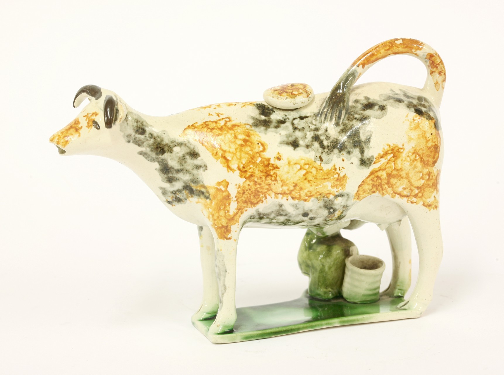 A Yorkshire pottery Cow Creamer,
c,1820, the beast standing four-square and sponged in ochre and