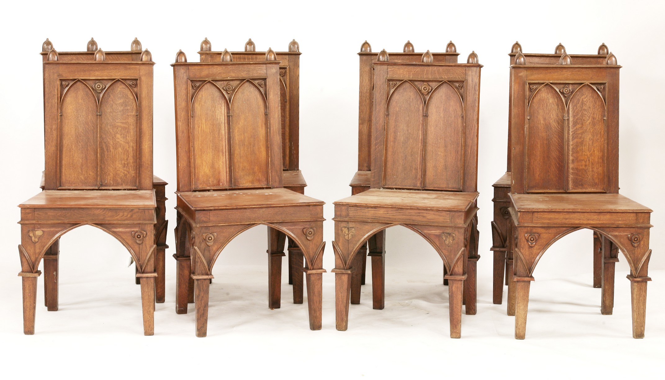 A set of ten Victorian oak hall chairs,
with blind tracery arcaded backs and triple acorn-shaped