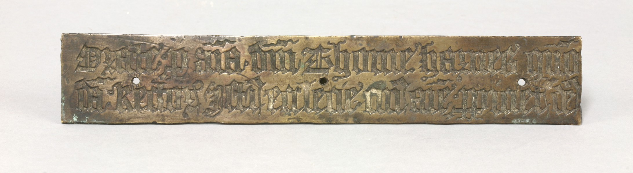 A brass panel,
possibly 16th century, engraved with Gothic script both sides, one reversed, with
