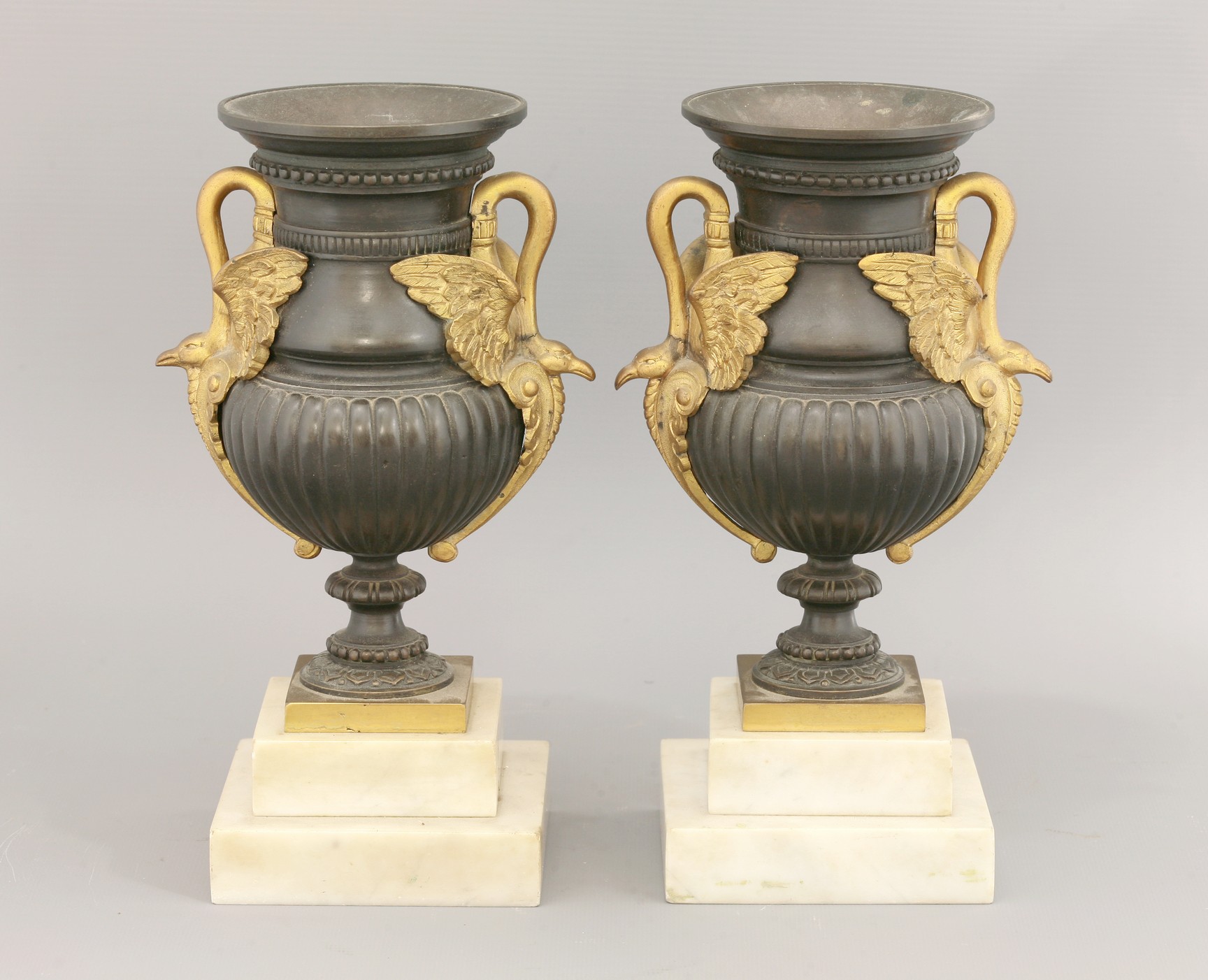 A pair of Empire-style bronze urn vases, 
with ormolu handles modelled as swans, upon stepped marble